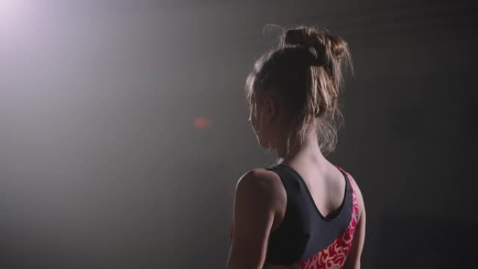年轻的女体操运动员站在体育馆的地板上，准备开始她的表演，体操比赛