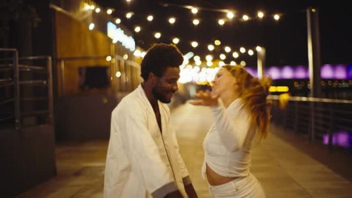 年轻多样的夫妇在潮湿的城市街道上表演现代舞蹈。开心和微笑