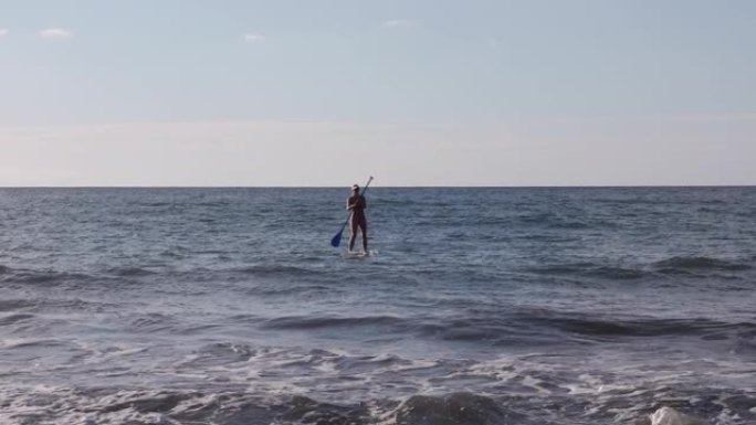 女性站立冲浪者 (SUP) 通过冲浪划桨