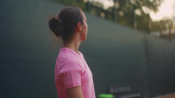 一名女子网球运动员在比赛结束后在球场上疲惫地向前看，在一场艰苦的比赛后集中注意力