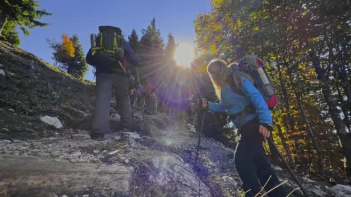 SLO MO男女徒步旅行者在陡峭的山间小径上穿越阳光充足的森林