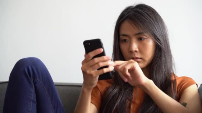 亚裔美国妇女在手机上做个人理财的中景肖像
