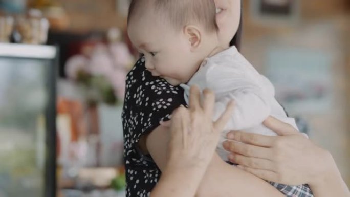 年轻的亚洲妈妈抱着她可爱的男婴