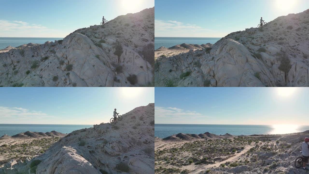 男子将山地自行车抬上岩脊的鸟瞰图