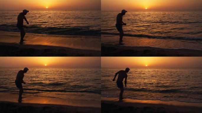 男人在海滩上的剪影以慢动作将石头扔进海中