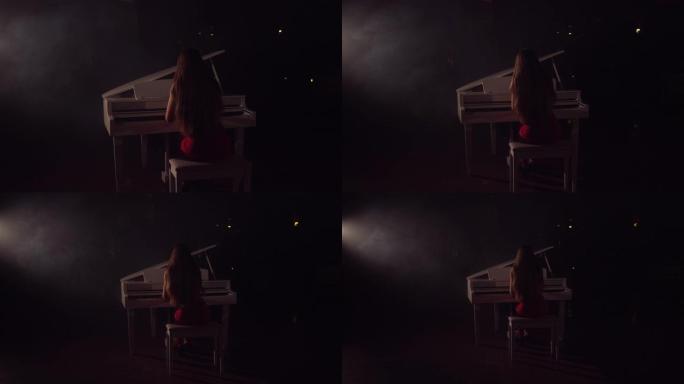 4k女钢琴家的镜头在音乐会舞台上演奏美丽的三角钢琴。一个女人在音乐厅弹钢琴。舞台灯光和背景上的轻雾