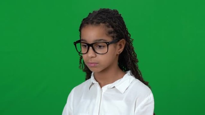 心烦意乱的书呆子非裔美国少女在绿屏上低头。在chromakey背景下戴眼镜的悲伤沮丧绝望的受歧视少年