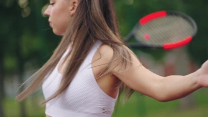 年轻的黑发女子正在网球场上训练和练习击球，慢动作射击