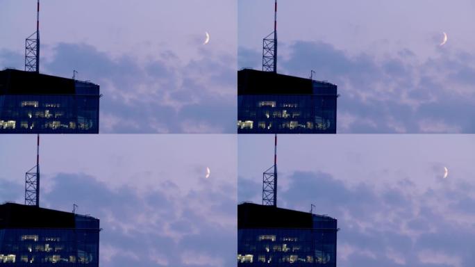 黄昏时现代摩天大楼顶部的空中拍摄，带有可见的新月