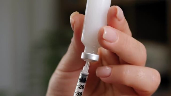 患有糖尿病的妇女用注射器和胰岛素在手边特写。