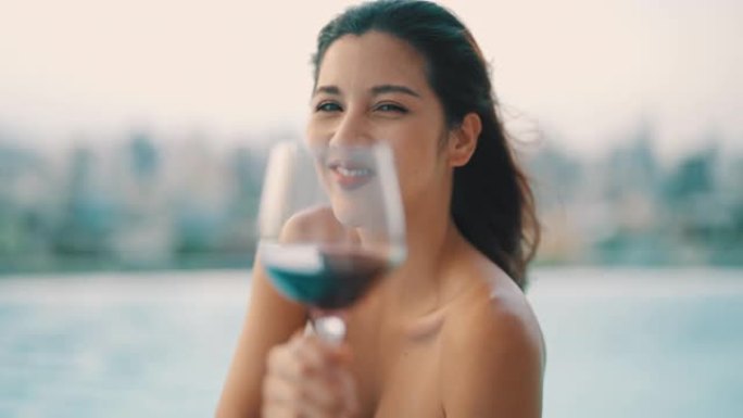 女人在游泳池里享受夏日，喝红酒。