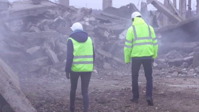 地震后废墟上绿色背心上救援信号的两名员工