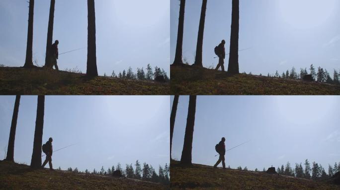 手握杆子的渔夫独自行走在大自然中，在蓝天下的剪影，慢动作拍摄