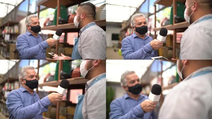 戴口罩的电视记者采访花园商店员工
