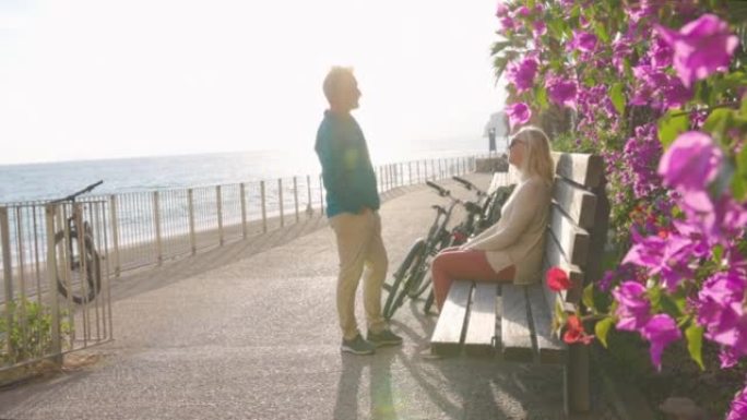 成熟的夫妇沿着海滩长廊推自行车