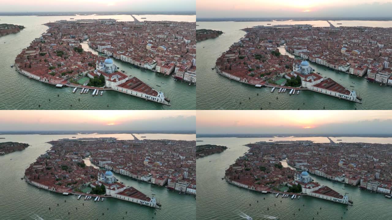 无人机日落场景的圣玛丽亚德拉致敬罗马天主教教堂和小大教堂与交通船之间的大运河和朱代卡运河