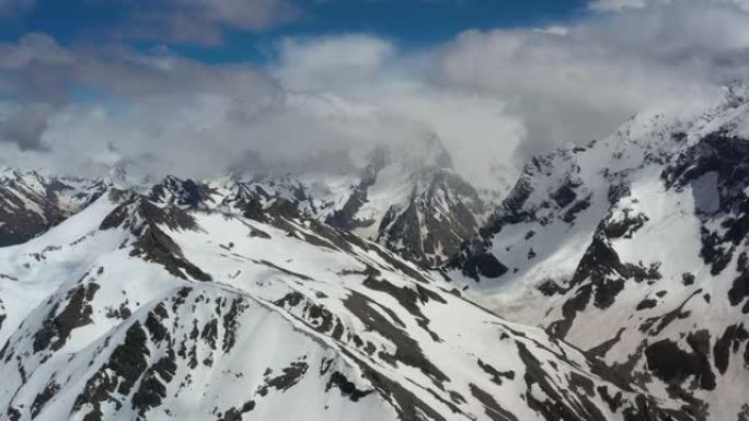 空中飞行穿过山云，飞越美丽的白雪皑皑的山峰和冰川。