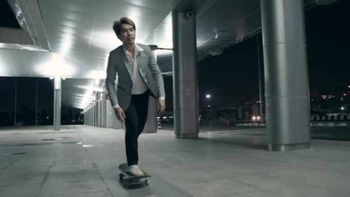 亚洲男子晚上在大城市骑着滑板上下班。