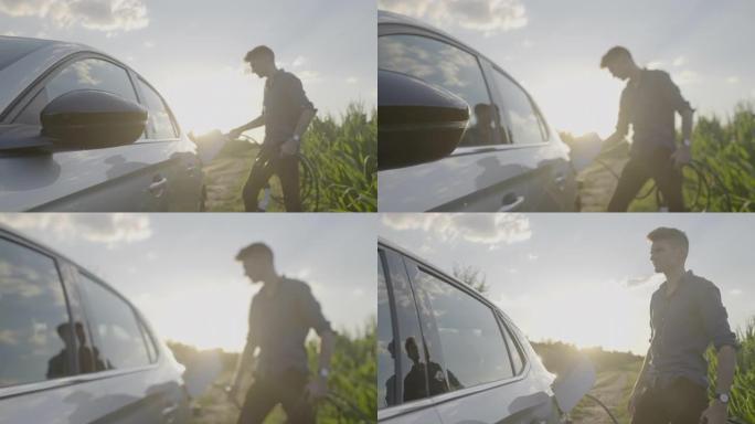 日落时分，男子站在玉米地，为电动汽车充电