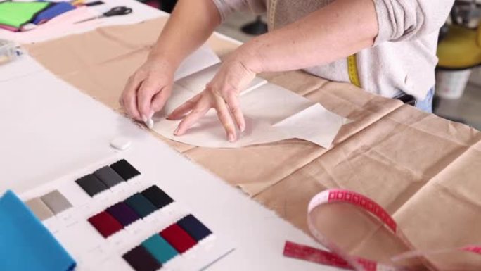 无法辨认的女裁缝在工作室用粉笔标记织物上做衣服