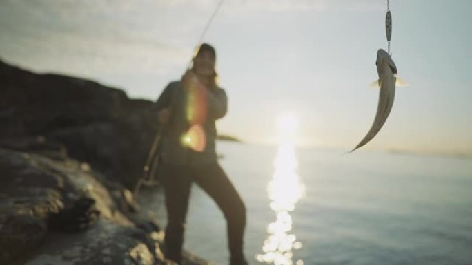 挪威的户外活动: 女人用鱼竿在海里钓鱼