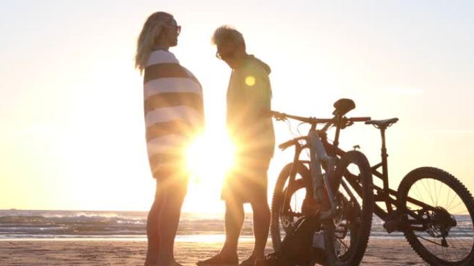 骑自行车的夫妇在空旷的海滩上享受放松的时光