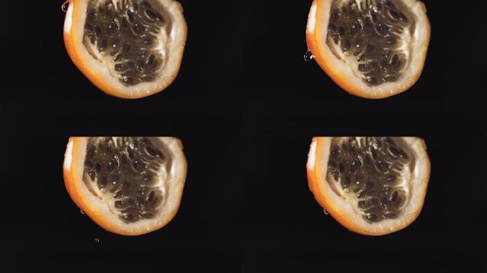 慢动作微距拍摄来自黑色背景中的一半的格拉纳迪拉汁的流动格拉纳迪拉汁