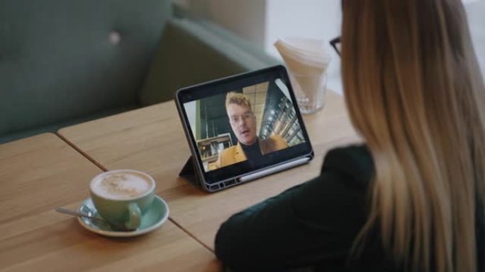 金发女子正在与男友或同事男子通过视频通话聊天，独自坐在咖啡店里