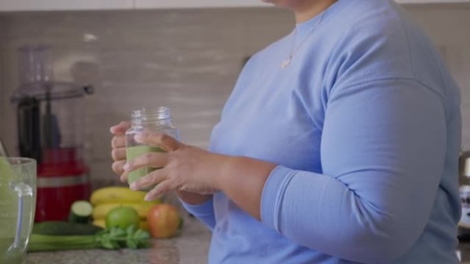巴西妇女在厨房喝排毒冰沙以减少身体超重。做锻炼后提神。