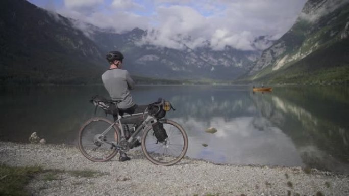 骑自行车的人停在湖边，欣赏山脉的景色