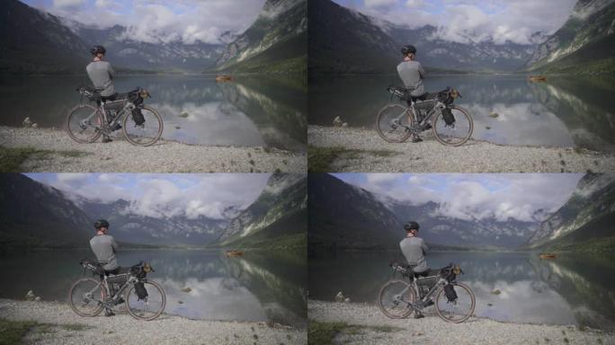 骑自行车的人停在湖边，欣赏山脉的景色