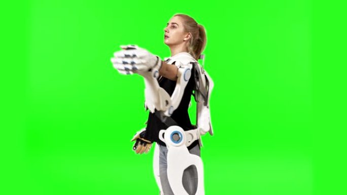 未来就是现在。戴着外骨骼的女人被隔离在绿色屏幕上。展开武器
