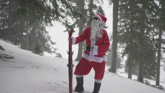 男子打扮成圣诞老人，站在白雪皑皑的森林里，带着一双滑雪板
