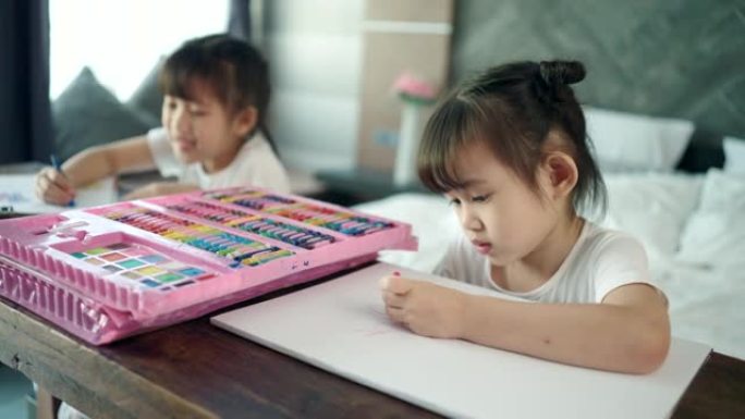 两个女孩在木桌上画画。