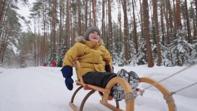 冬天在白雪皑皑的森林里骑雪橇的慢动作3-4岁微笑男孩的肖像