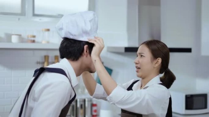 年轻夫妇戴着厨师帽和围裙
