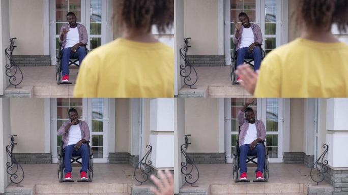 微笑着残疾的非洲裔美国父亲坐在轮椅上向十几岁的女儿告别。女孩离开时，骄傲快乐的父母在户外前院门廊上的