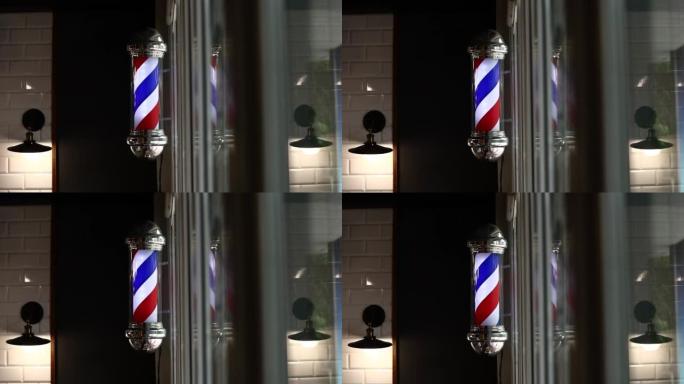 理发杆在晚上旋转。国际理发店杆子标志。理发杆在街上呼唤人们。老式理发店。沙龙