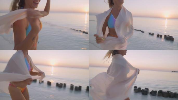 诱人的女人戴着精致的围巾跳舞。田园诗般的，日落时的热带海滩