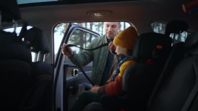 乘汽车旅行，父亲将女儿放在汽车上，并系好儿童座椅上的安全带。带孩子的汽车安全旅行