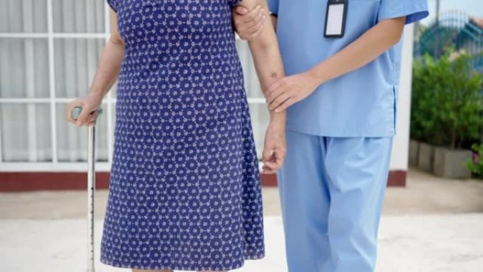 特写女护士帮助老人用拐杖走路，进行物理治疗。