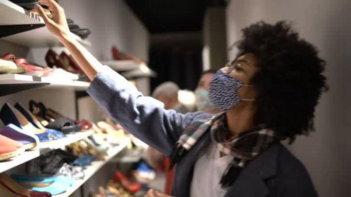 戴着口罩的年轻女子在旧货店买鞋时得到了女售货员的帮助