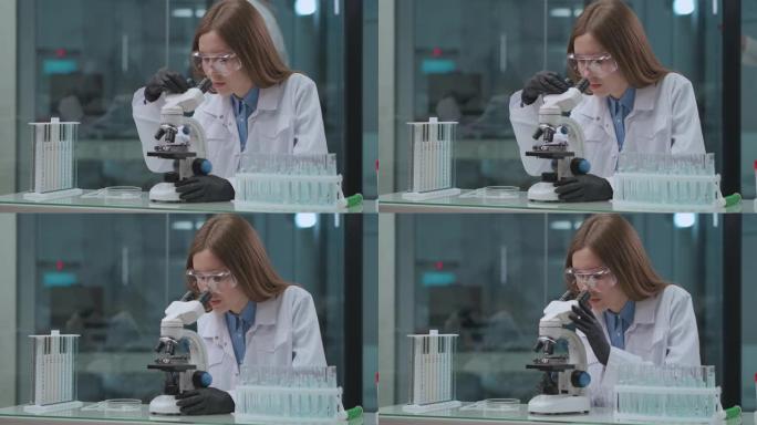 年轻的女性健康专业人员正在实验室工作，使用现代显微镜测试来自新型冠状病毒肺炎的新疫苗