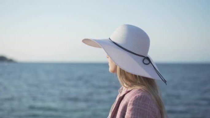 戴着白帽子的年轻女子在阳光明媚的日子里看着海景