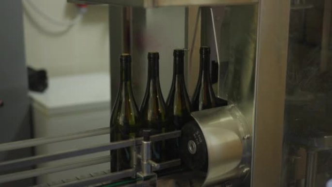 酒庄生产线上的酒瓶侧视图。葡萄酒厂室内的美味酒精饮料包装。酿酒概念。