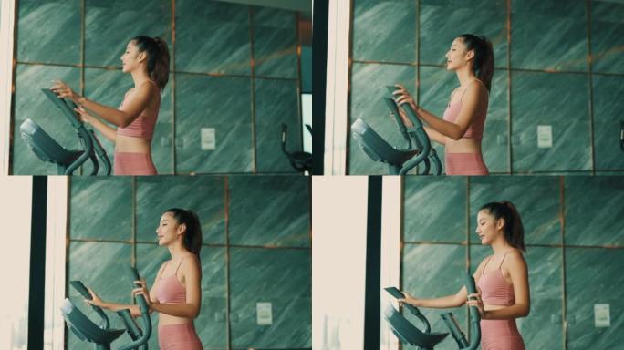 美丽的女人在健身房用椭圆步行机锻炼