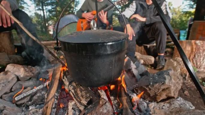 SLO MO一群朋友在篝火上的铸铁锅里做饭