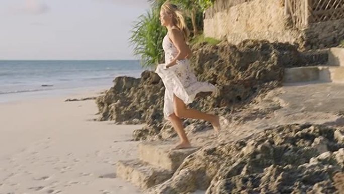 海滩漫步。穿着夏装的女人在热带岩石海岸线享受日落