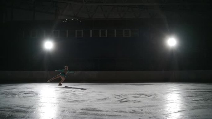 单人花样滑冰少年冠军女孩在空冰场独自滑冰，晚上训练，准备夺冠