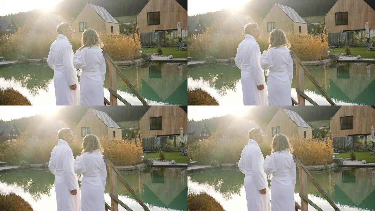 男人和女人站在池塘旁，穿着白色毛巾的桑拿浴室